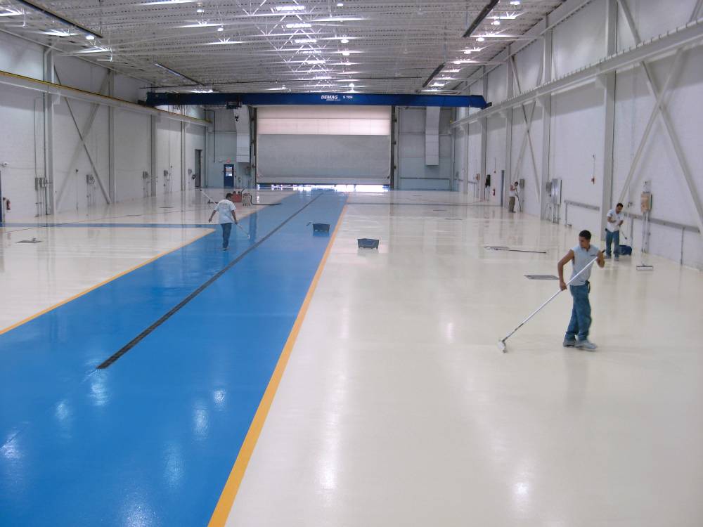 Final epoxy floor coating is applied to a second hangar. Note the traffic aisle is delineated in blue.