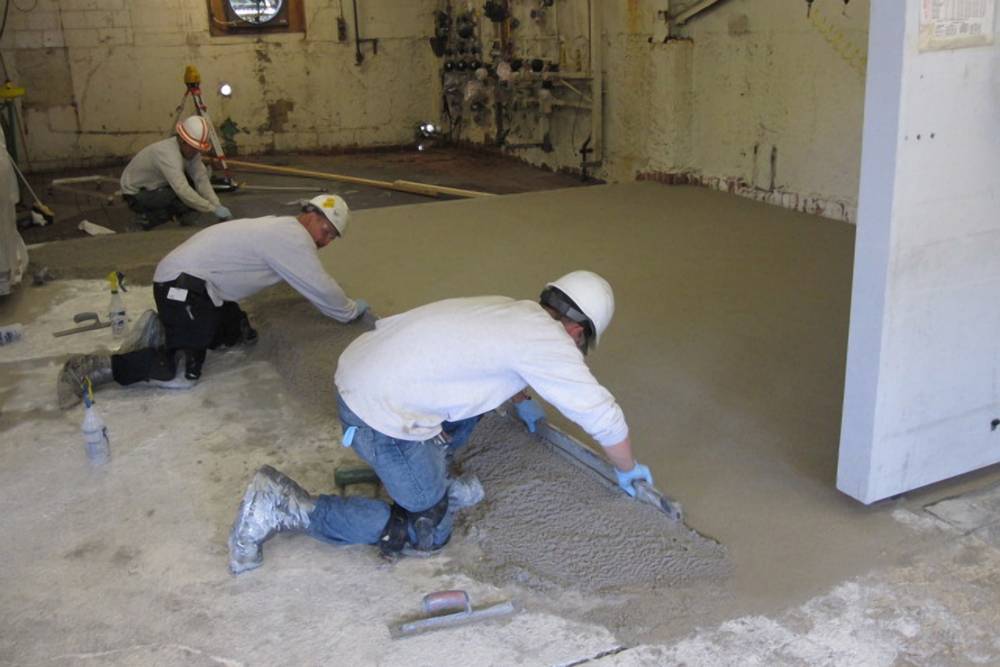 Here the PermaFloor crew uses a screed to level the rough surface.