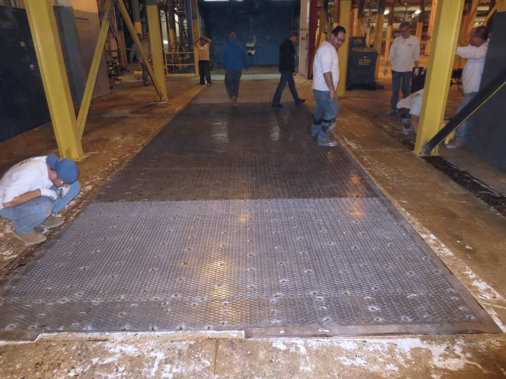 The metal deck outside of a shot blasting booth for heavy equipment was creating a slip hazard when metal shot from the booth would accumulate. Additionally, concrete around the deck was spalled.